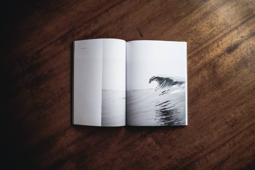 Imagen ornamental que muestra un libro abierto con una ola marina en blanco y negro, por Andrew Neel en Unsplash, CC0